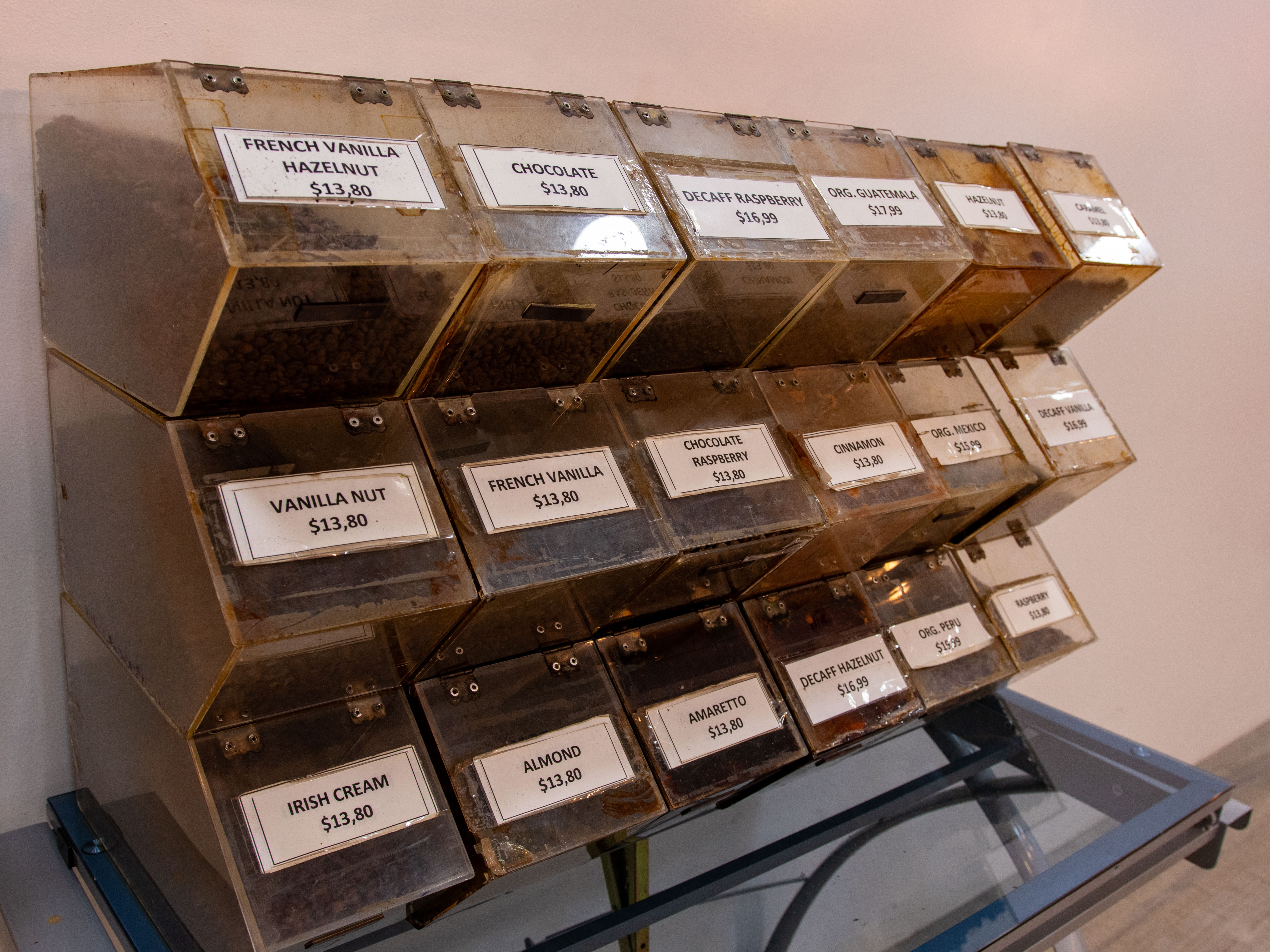 A selection of coffee blends in transparent boxes, each with a price tag, including French Vanilla, Chocolate, Decaf Raspberry